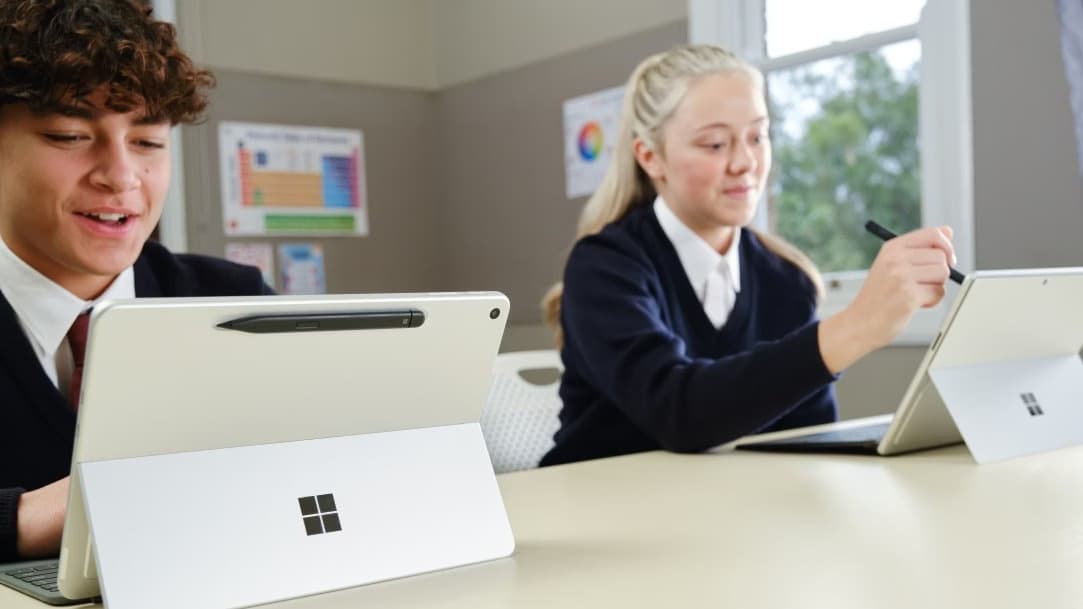Professional business man and woman in formal attire working together on a laptop in a premium modern office.